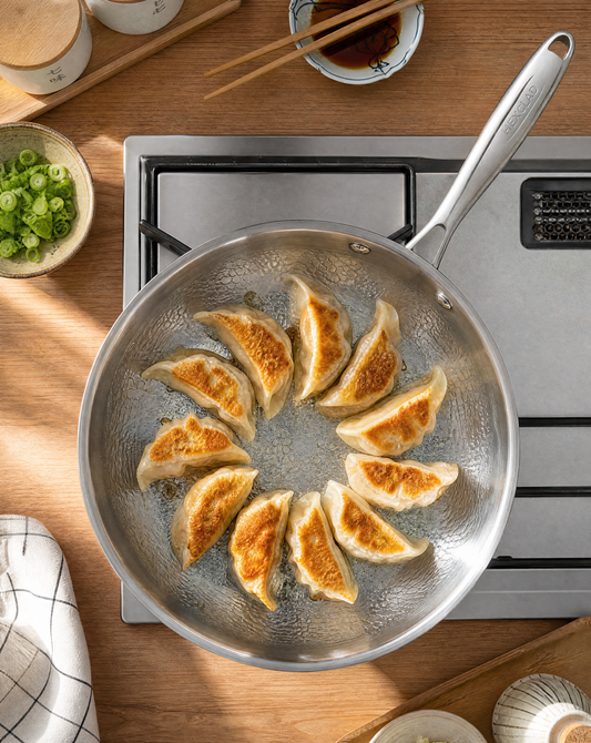 Gyoza browning evenly in a titanium frying pan